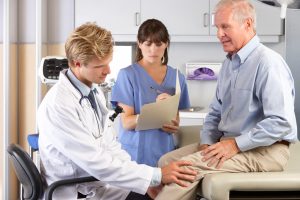Male Doctor Examining Male Patient With Knee Pain